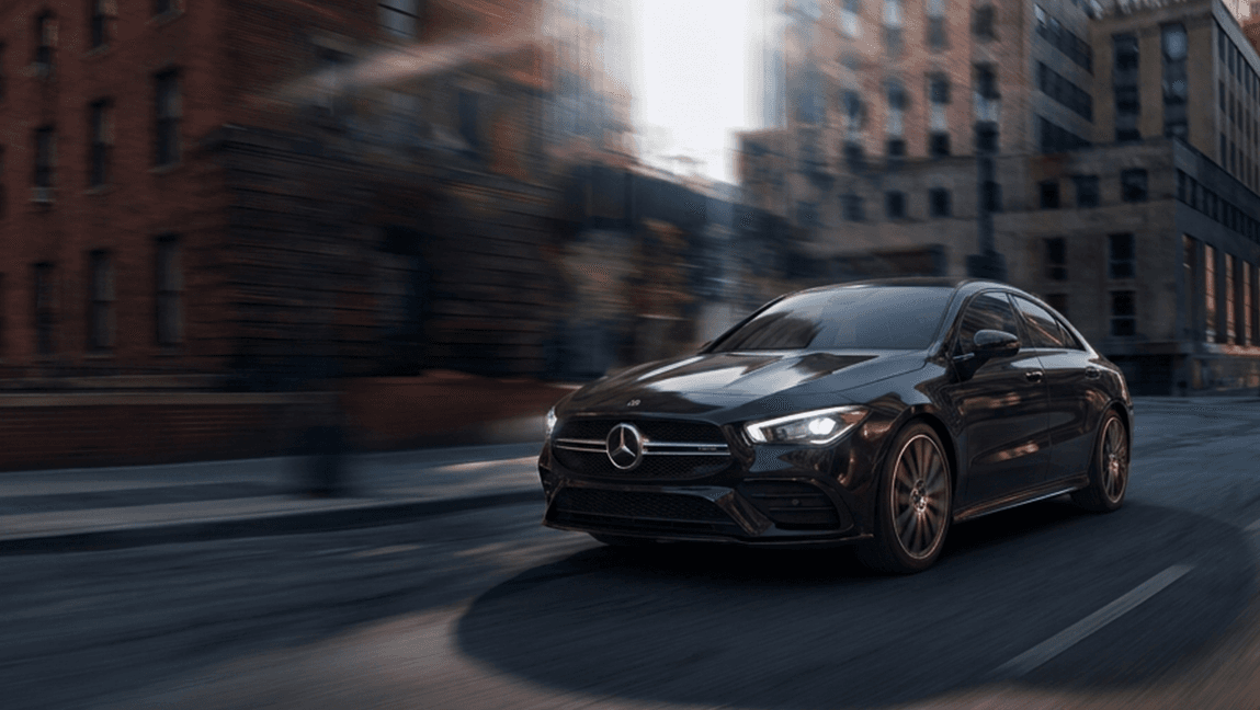 Mercedes-Benz CLA negro circulando por una calle urbana al atardecer